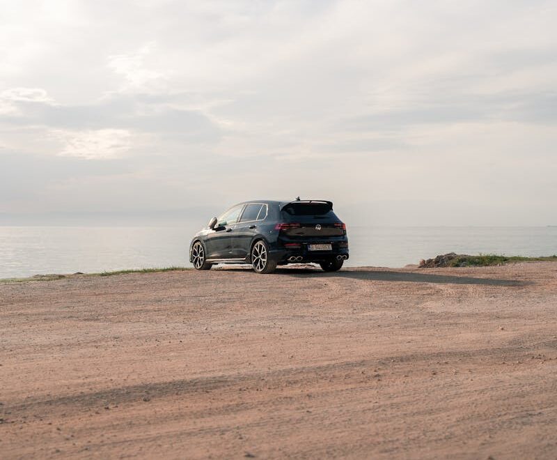 Une voiture garée sur une route calme du désert au bord de la mer, capturant l'aventure en plein air et la tranquillité.